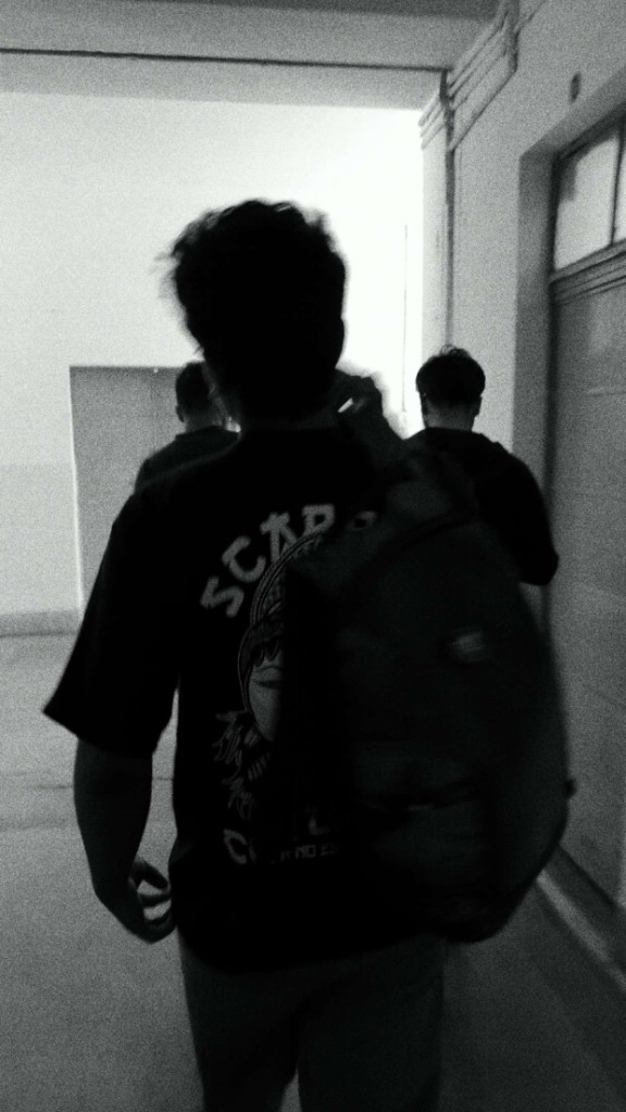 Salil Lakra walking down a hallway, photographed from behind
